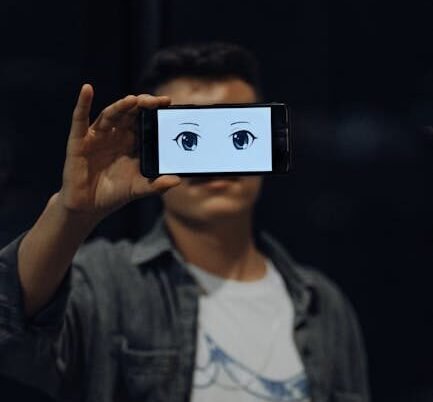 A person holds a smartphone displaying anime eyes, obscuring their face, wearing a denim jacket.