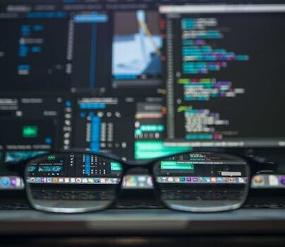 Eyeglasses reflecting computer code on a monitor, ideal for technology and programming themes.